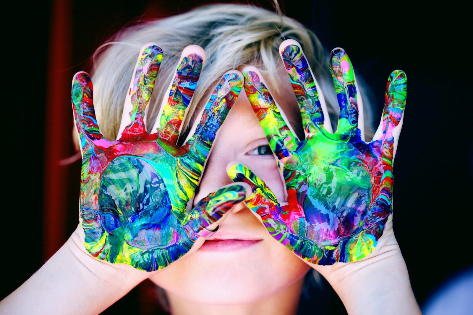 young child with palms covered in bright colored paint
