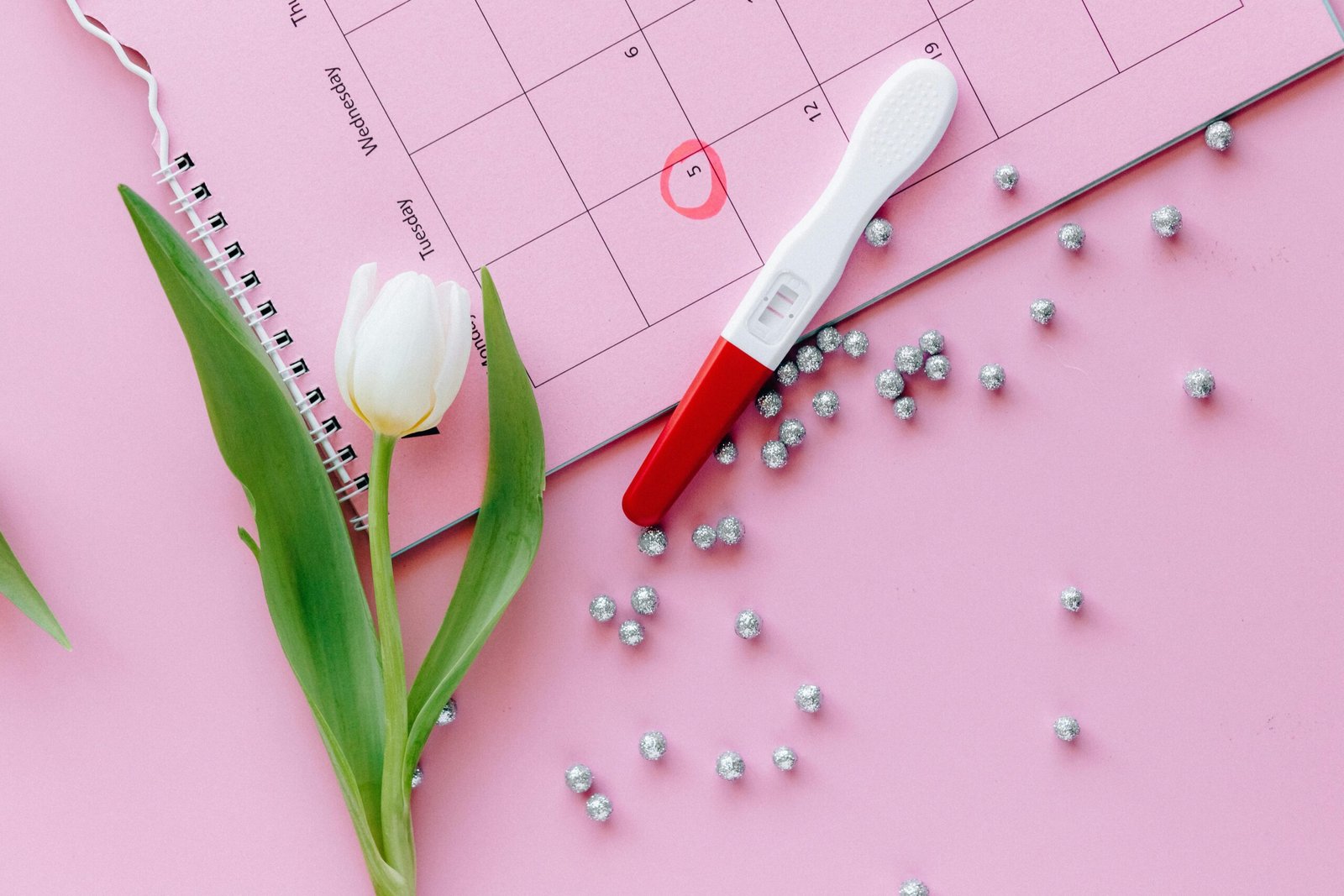 a positive pregnancy test with on a pink calendar